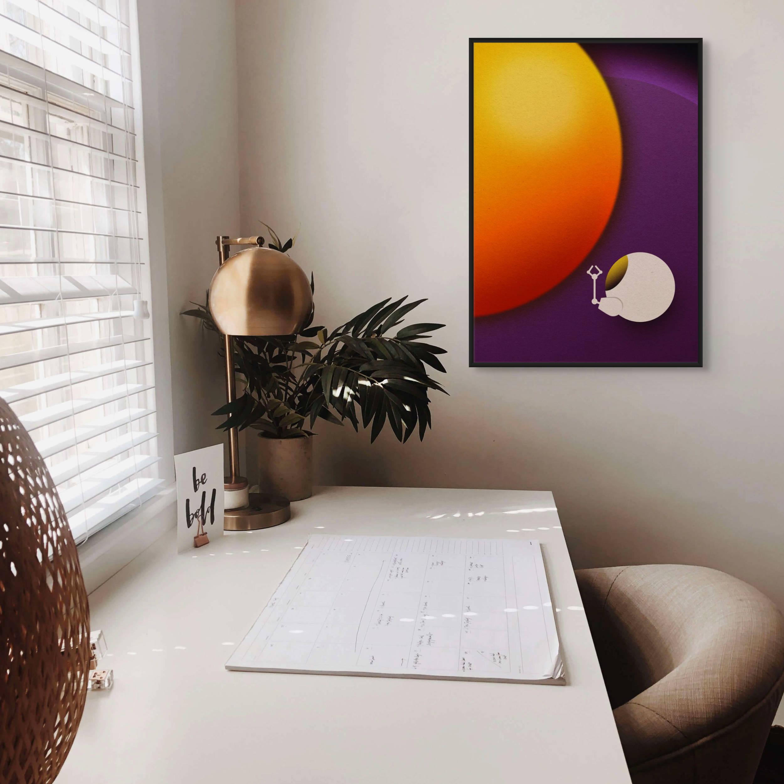 Framed minimalist space art print displayed in a modern home workspace with warm tones and mid century styling